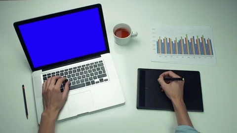 Top view male hands using graphic tab and laptop with green screen at white desk Stock Footage 82888849