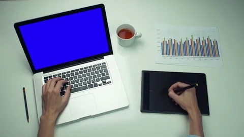 Top view male hands using graphic tab and laptop with green screen at white desk Stock Footage 82889017