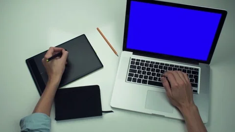 Top view male hands using graphic tab and laptop with green screen at white desk Stock Footage 82890596