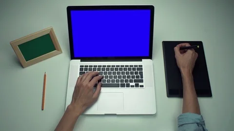 Top view male hands using graphic tab and laptop with green screen at white desk Stock Footage 82894041