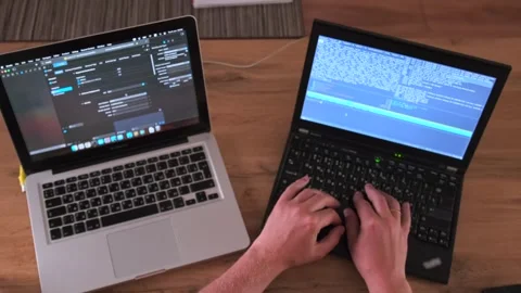 Top view of male hands that work on two laptops at once typing program code. Stock Footage 243583978