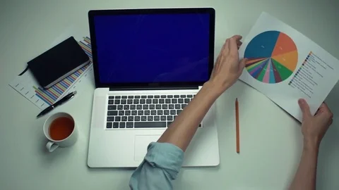 Top view male hands working with printed graphs using laptop with green screen Stock Footage 82891491