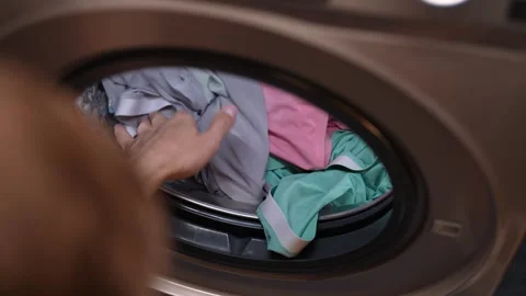 Top view of male loading dirty clothes into modern washing machine in home Stock Footage 293251742