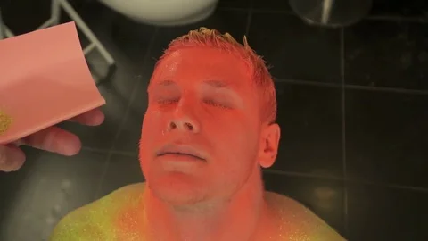 Top view, man is being covered with the colored sparkles, slow motion Stock Footage 73542366
