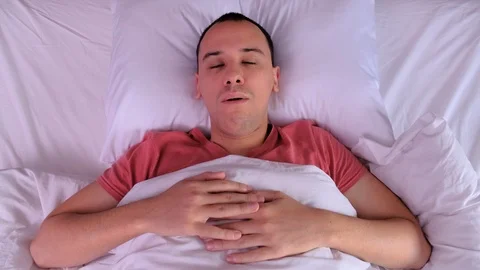 Top view. Man can't sleep from noise and covers. Covers his ears. Stock Footage 123500035