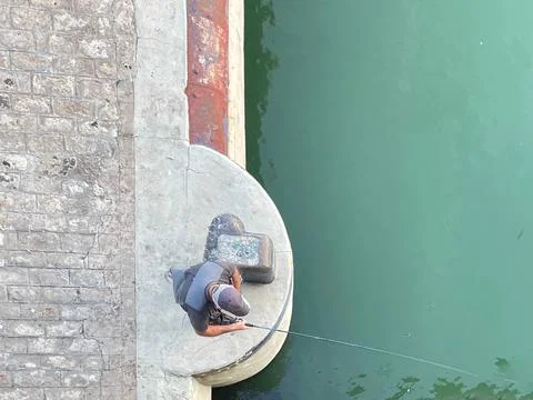 Top view of a man in a cap angling on the bank of a river. Stock-Fotos