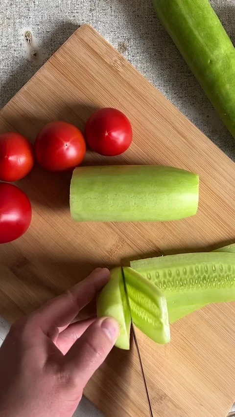Top view. Man cuts green fresh cucumber with knife on wooden cutting board Stock Footage 280482283