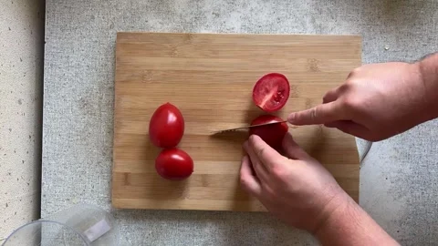 Top view. Man cuts red fresh juicy tomatoes with knife on wooden cutting board Stock Footage 276937084