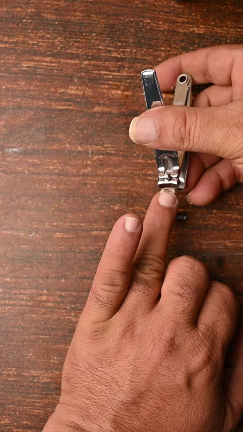 Top View of a Man Cutting Fingernails on Wooden Table Vertical Footage Stock Footage 329341775