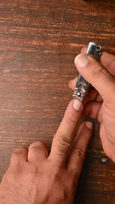 Top View of a Man Cutting Fingernails on Wooden Table Stock Footage 329350460