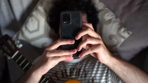 Top view of a man with guitar lying on a sofa and using a phone. Stock Footage 162169290