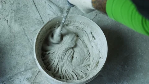 Top view of a man hand with an electric hand mixer stirring plaster in a bucket Stock Footage 167682305