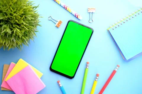 Top view of man hand using smart phone with stationary on blue background Stock Photos