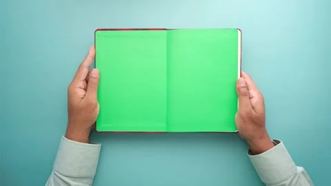 Top view of man hands holding open book with green screen, copy space, isol.. Stock Footage 333153772