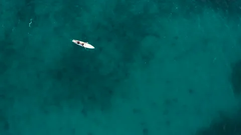 Top view of a man laying on a paddle board on a calm sea in summer Stock Footage 132764011