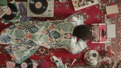 Top View of Man Lying on Floor, Typing on Retro Typewriter and Enjoying Music Stock Footage 339851539
