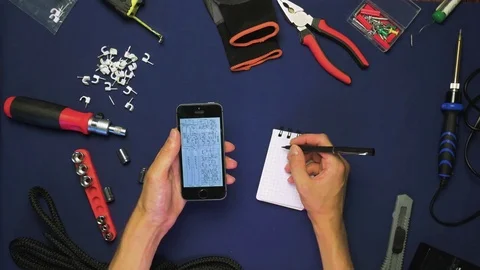 Top view man (man's hands) scrolling a variation schemes on a phone than writing 動画素材 78603605