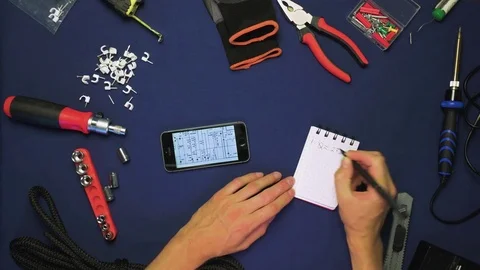 Top view man (man's hands) scrolling a variation schemes on a phone than writing 動画素材 78603632