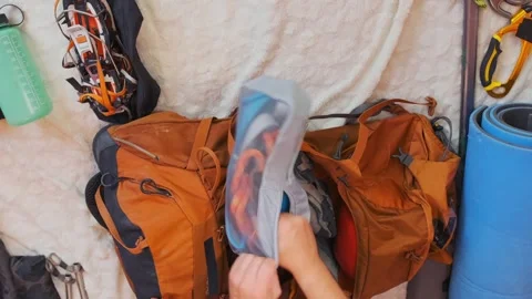 Top view man packing climbing gear into backpack, organizing mountaineering Stock Footage 333471131