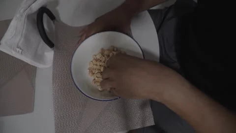 Top view of a man peeling peanuts into a bowl Stock Footage 320966220