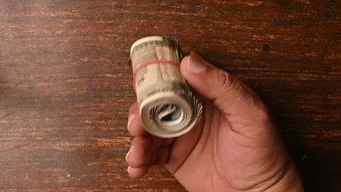 Top View of a Man Placing 500 Rupee Round Bundle on Wooden Table Stock Footage 329343858