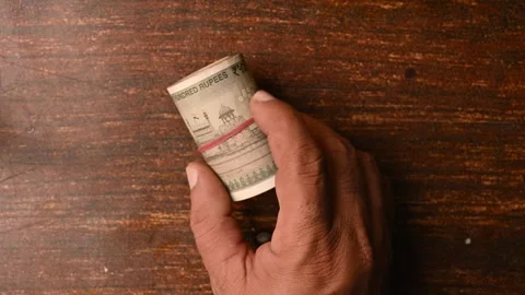 Top View of a Man Placing 500 Rupee Round Bundle on Wooden Table 스톡 동영상 329344535