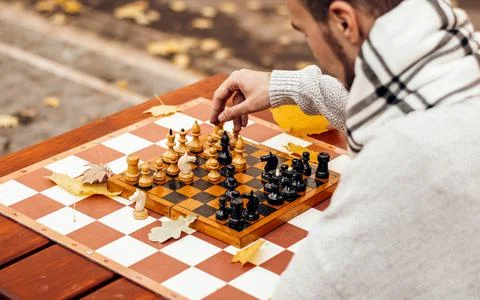 Top view: a man plays chess on a table in an autumn park at the play area Stock Photos