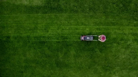 Top view of the man pushing lawn mower for cutting grass in garden with sunlight Stock Footage 232677404