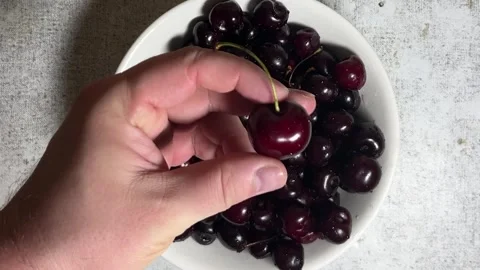 Top view. Man puts red cherries to white bowl Video stock 290289201