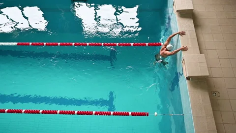 Top view of man reaching pool edge after swimming in indoor lap pool Stock Footage 346769600