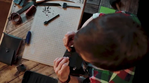 Top view of a man sewing a black wallet with his own hands with a needle, thread Stock-Footage 146350397