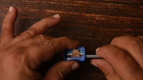 Top View of Man Sharpening Pencil with Sharpener on Wooden Table Stock Footage 329342812