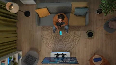 Top view of man sitting on the sofa looking up, holding smartphone with app for 写真素材