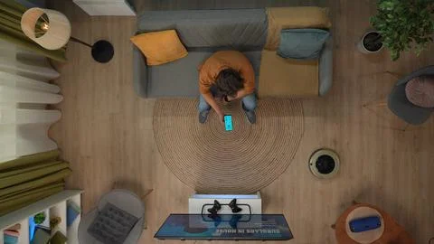 Top view of man sitting on the sofa looking at vacuum cleaner, holding 写真素材