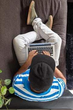 Top view of a man sitting on a sofa working on his laptop 库存照片