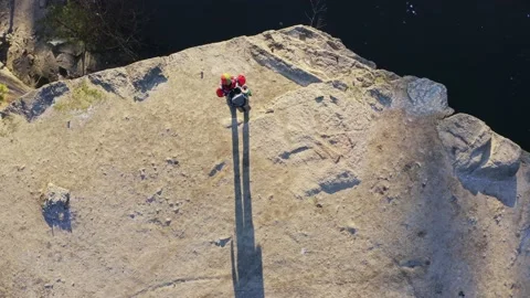 Top view man stands one edge of quarry with a lake Stock Footage 203842839
