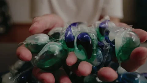 Top view of man taking and holding laundry detergent capsules sitting at table Stock Footage 313297846