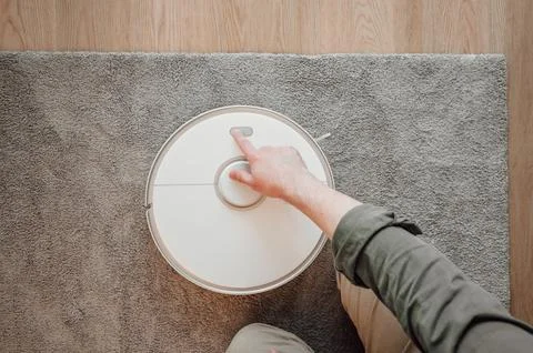 Top view on man turning on robot vacuum cleaner. smart home concept Stock Photos