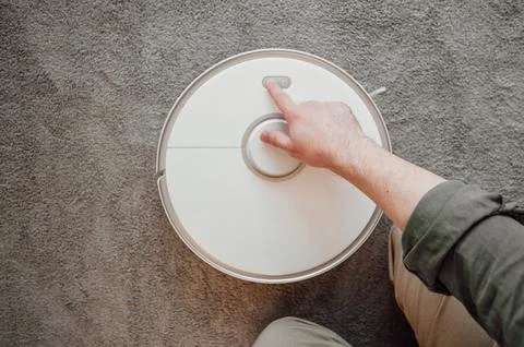 Top view on man turning on robot vacuum cleaner. smart home concept Stock Photos
