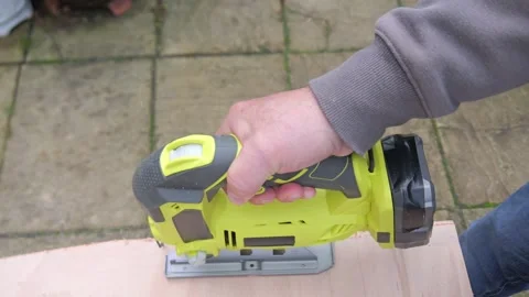 Top view of a man using a battery powered Jigsaw cutting a board on a work .. Video stock 321001724