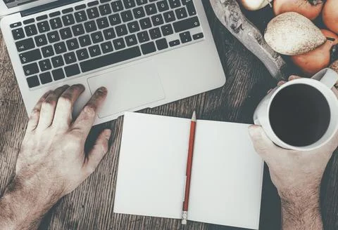Top view of man using laptop computer while holding cup of coffee against rustic Stock Photos