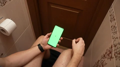 Top view of man using smartphone with green screen while sitting in restroom Vídeos de archivo 325803718