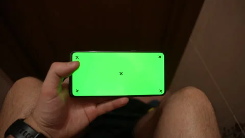 Top view of man using smartphone with green screen while sitting in restroom Vídeos de archivo 325803777