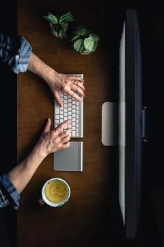 Top view of a man working at a computer in a dark room at night. Stock Photos