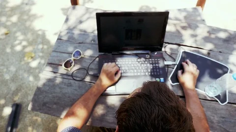 Top view of a man working on his laptop by wooden table next to bottle of water Stock Footage 88346061