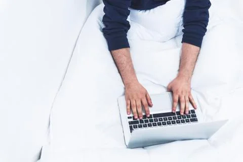 Top view of a man working on his lap top the the bed Stock Photos