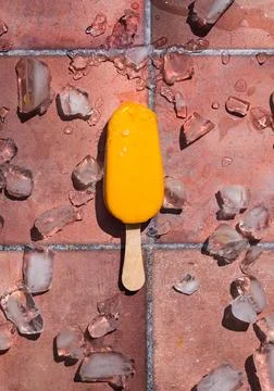 Top view of a mango popsicle on terra cotta tile in the sun. Stock Photos