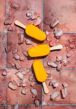 Top view of mango popsicles on terra cotta tile in the sun. Stock Photos