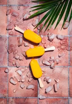 Top view of mango popsicles on terra cotta tile in the sun. Stock Photos