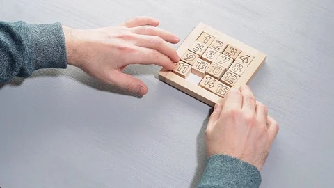 Top view on man's hand solves the conundrum on the gray wooden table. Stock Footage 101161434